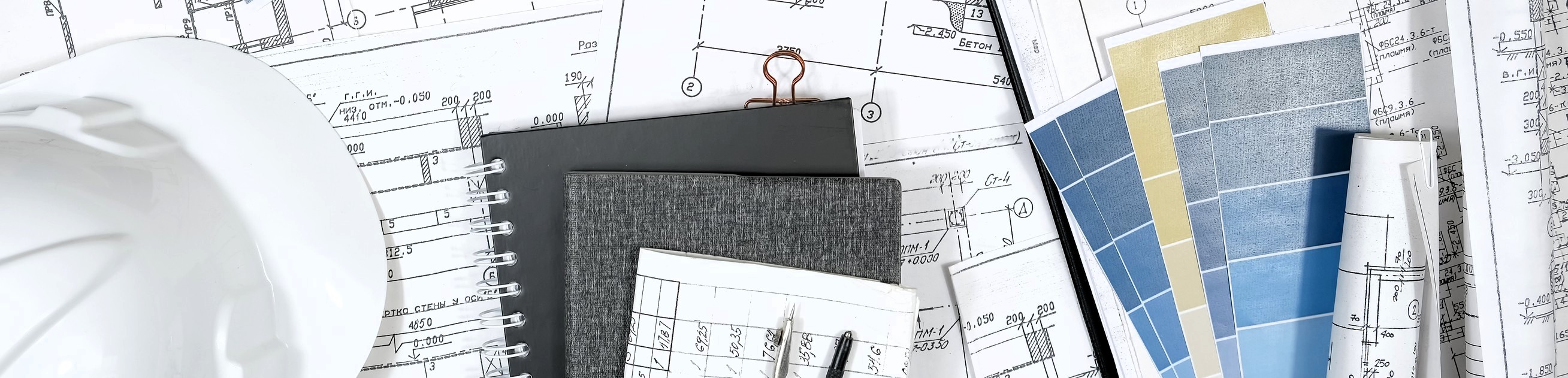 Workspace with construction blueprints, blue and tan paint swatches, two gray notebooks, pens, and white hard hat